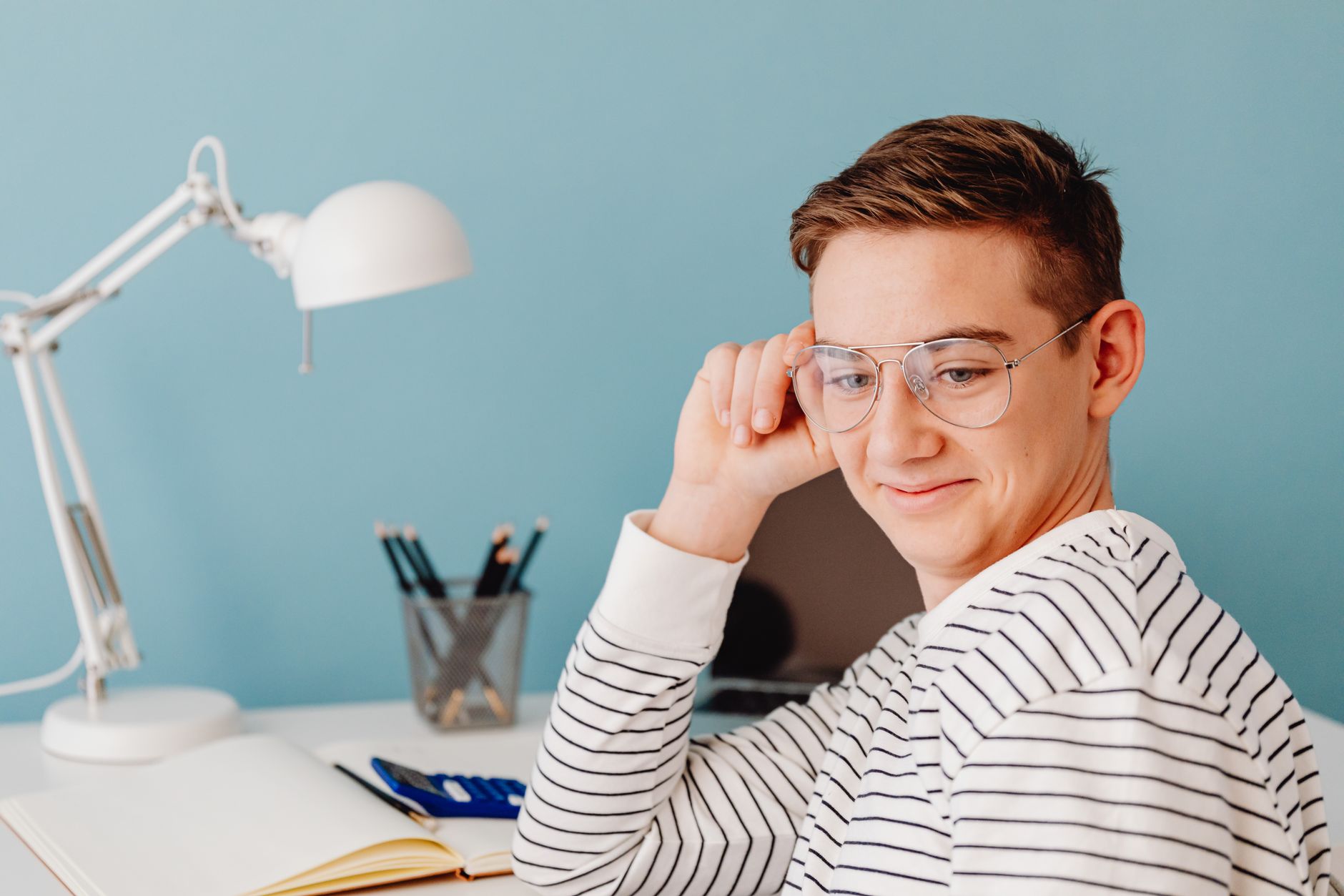 Casual and cheerful young man with eyeglasses working in a modern indoor setting.